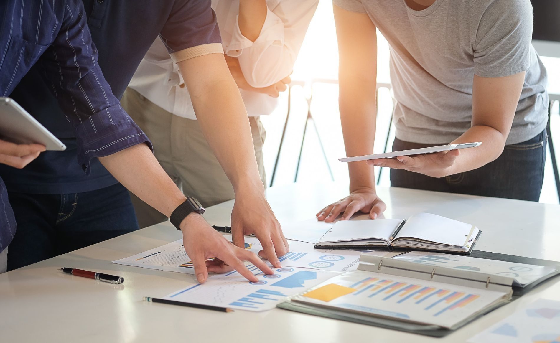 Un grupo de personas están de pie alrededor de una mesa mirando papeles.