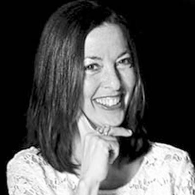 Una fotografía en blanco y negro de una mujer sonriendo y señalando su cara.